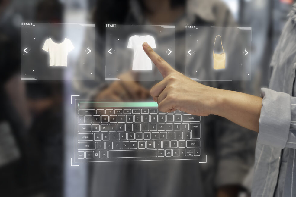 Une main utilise une interface numérique tactile pour sélectionner des vêtements et des accessoires sur un clavier virtuel en transparence