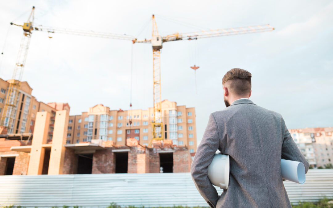 Entrepreneur de dos contemplant un grand chantier avec grues